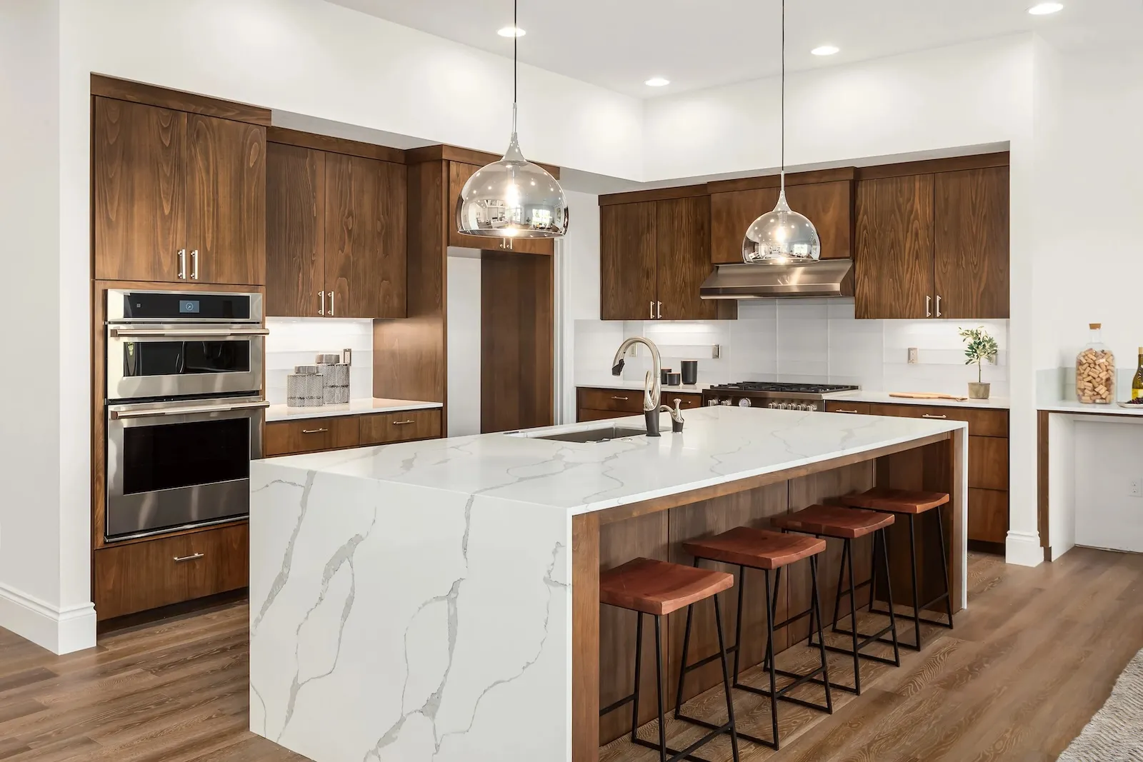Modern kitchen remodel in Oakville with custom walnut cabinetry, quartz waterfall island, stainless steel appliances, and pendant lighting by Leo Constra