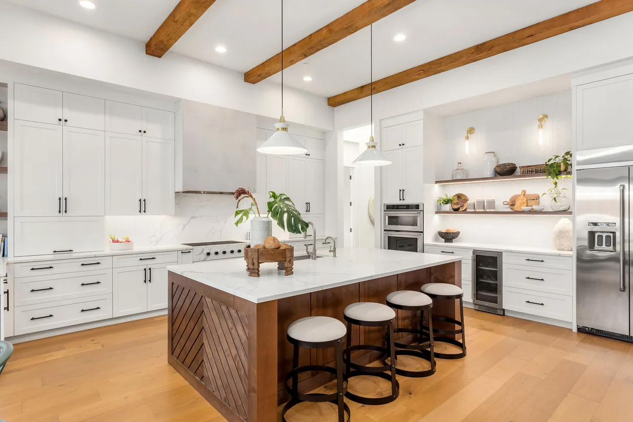 Bright kitchen renovation with white shaker cabinets, walnut island, exposed wood beams, and task lighting fixtures in Ontario