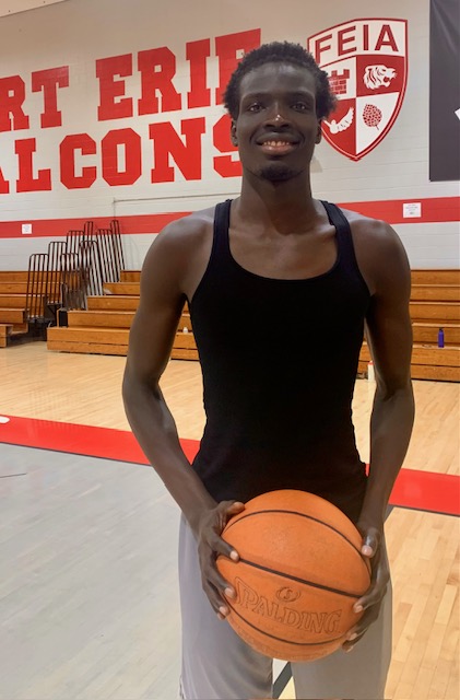Ajak Akech holding a basketball in the FEIA gym