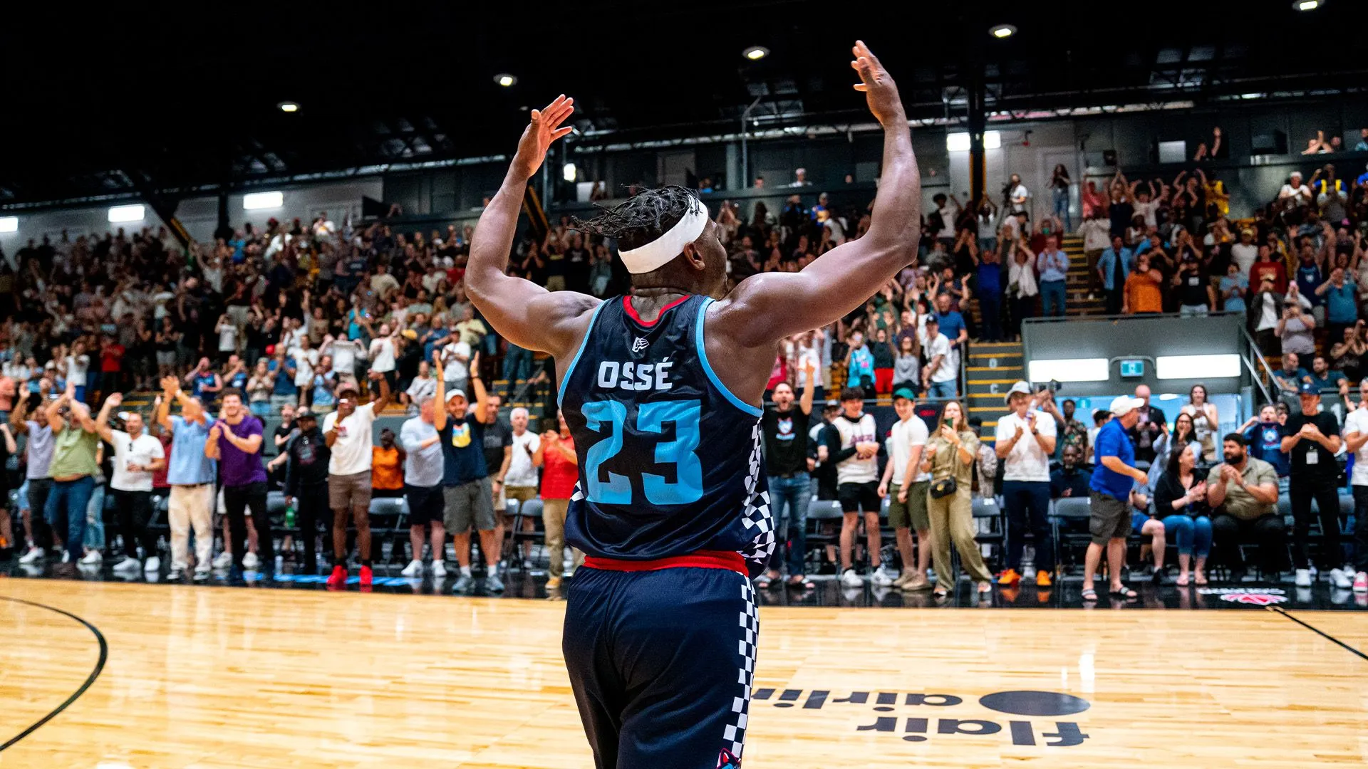 Kemy Ossé in his number 23 jersey raising his arms to a cheering crowd at a pro game