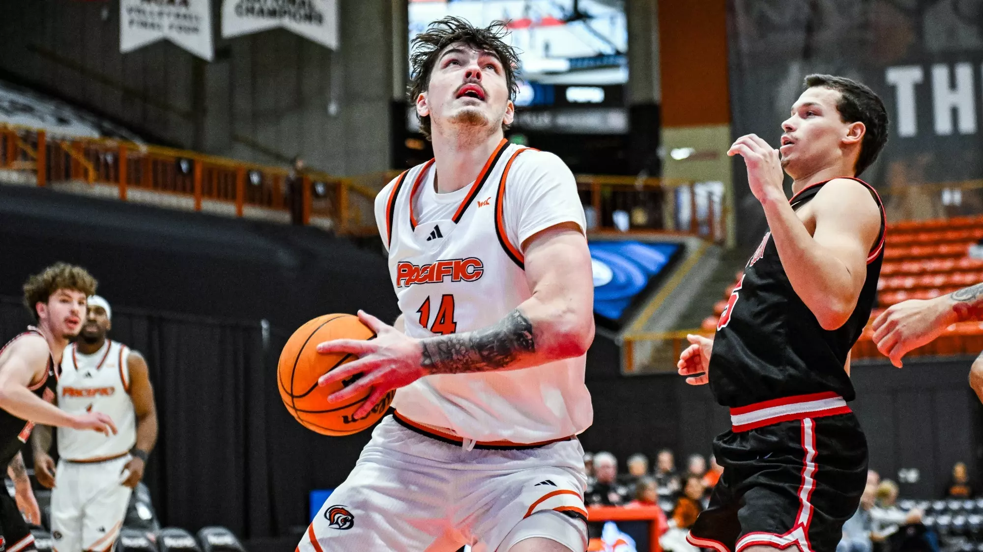 FEIA graduate Isaac Jack driving to the basket in a college game, ball in hand