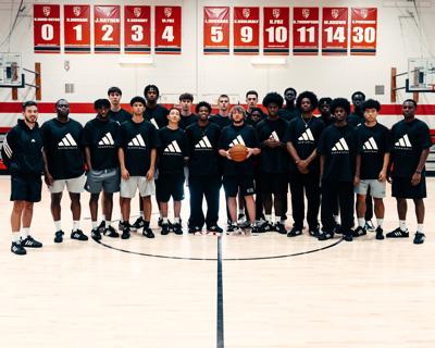 FEIA basketball team and staff in matching black Adidas shirts posed at centre court