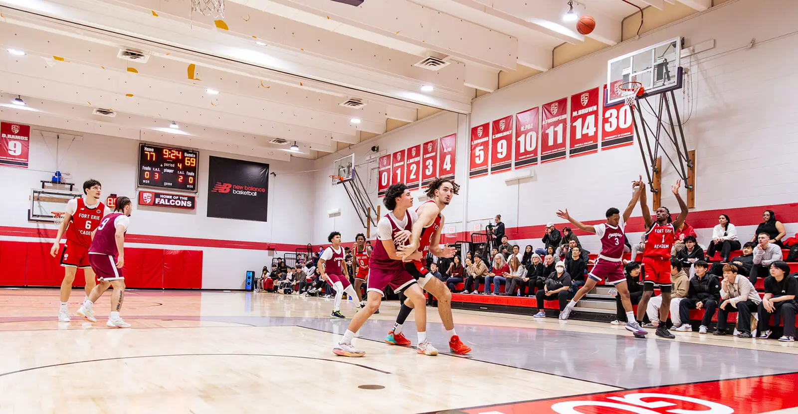 FEIA Falcons playing a basketball game in a gym with championship banners on the wall