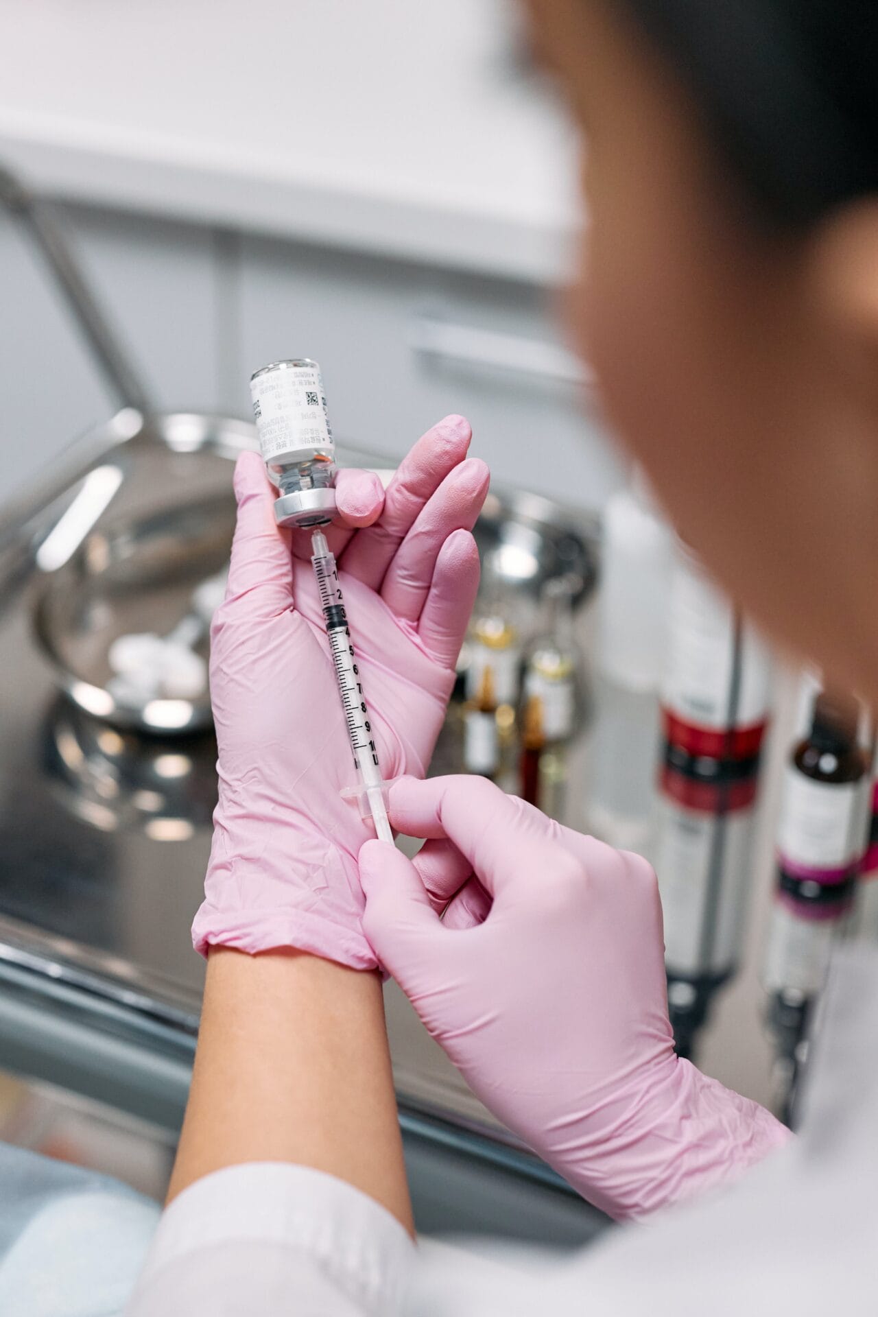 A woman in pink gloves expertly holds a syringe, providing a visual demonstration for beginners interested in cosmetic injectables.