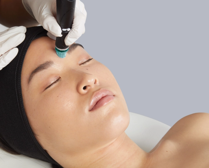 A person receiving a rejuvenating facial treatment on their forehead with a handheld device at Center MedSpa, wearing a black headband.