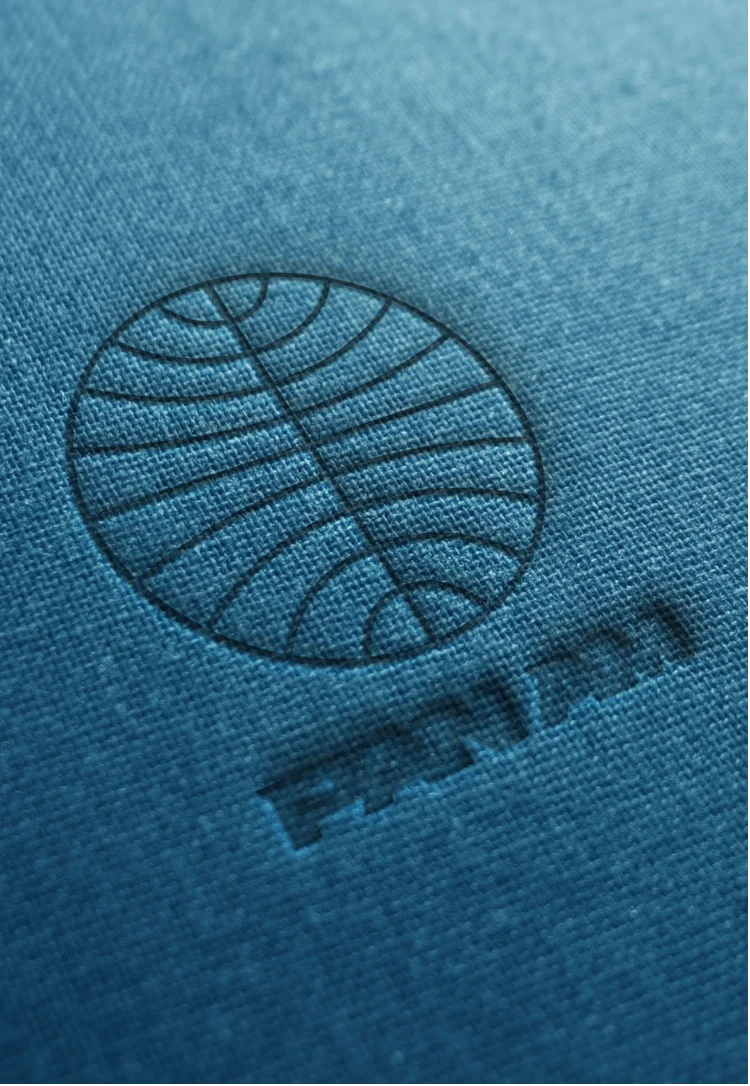 Embossed FEAT PAM logo with a circular design of curved lines on blue textured fabric.