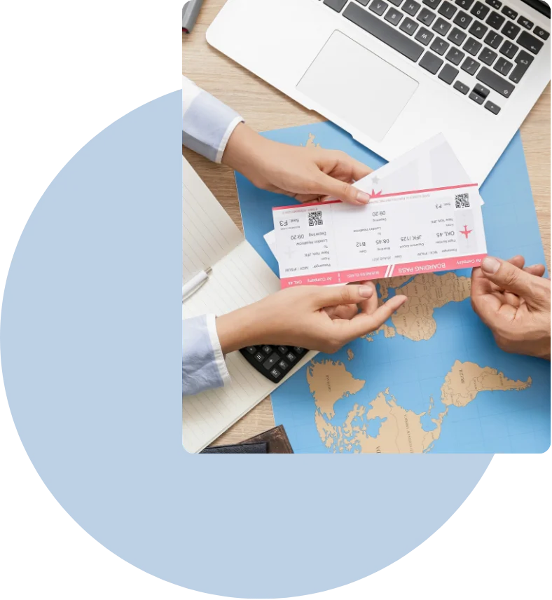 Two people holding plane boarding passes over a world map with a laptop and notebook nearby.