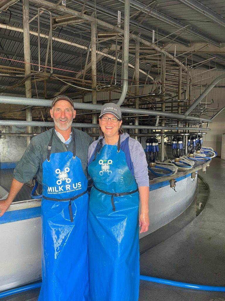 Two Farmers with milking aprons in a milking shed