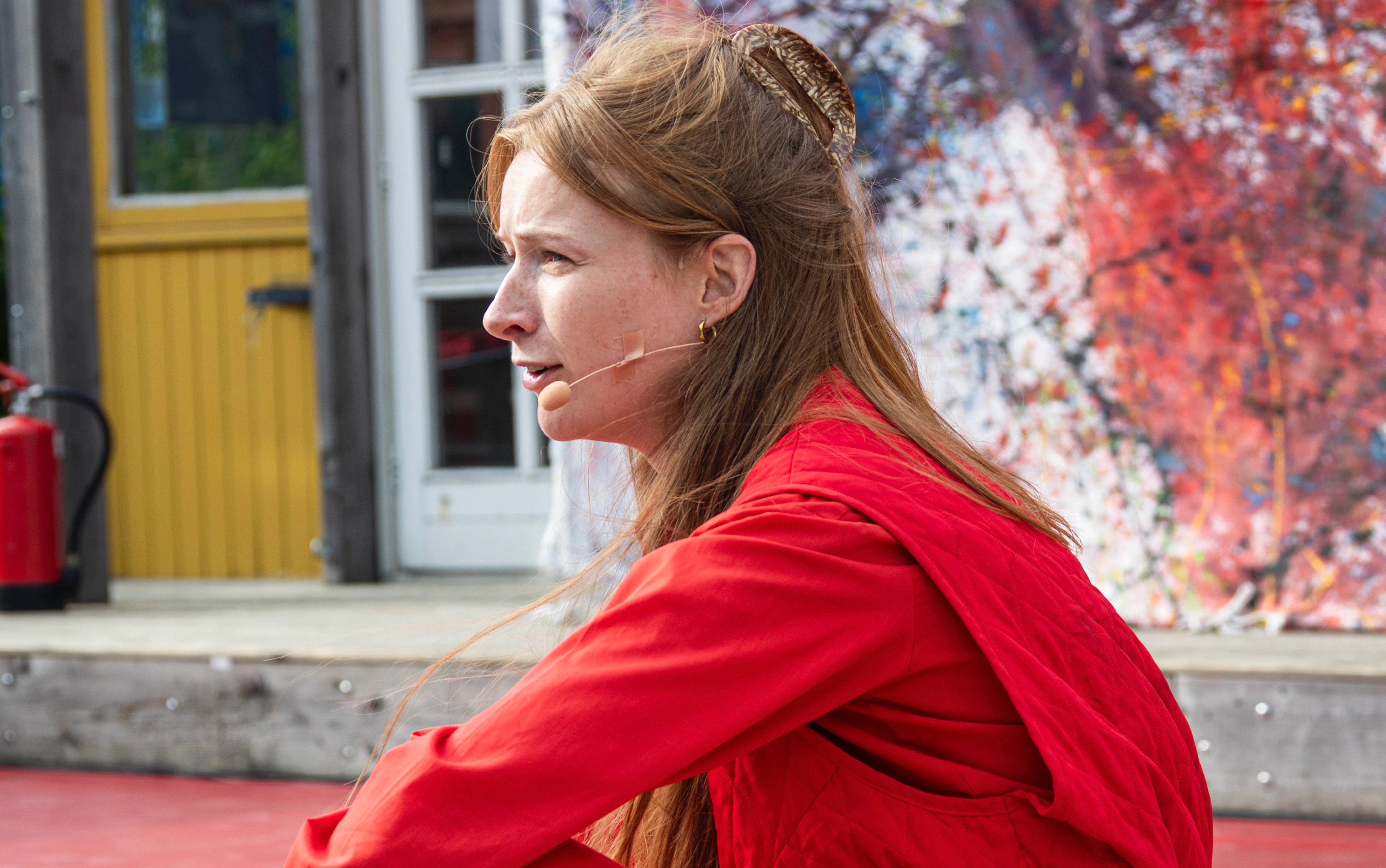 Vrouw in het rood gekleed voor een groot doek met verfspetters