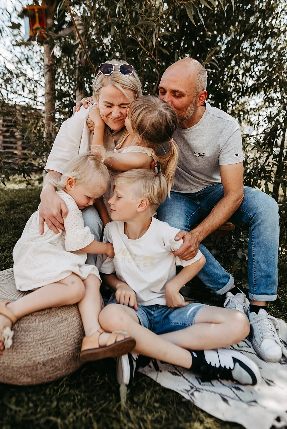 Glückliche Familie mit zwei Eltern und drei Kindern umarmt sich im Garten.