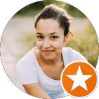 Porträt einer jungen Frau mit zusammengebundenen Haaren und weißem T-Shirt, lächelnd im Freien mit unscharfem Hintergrund.