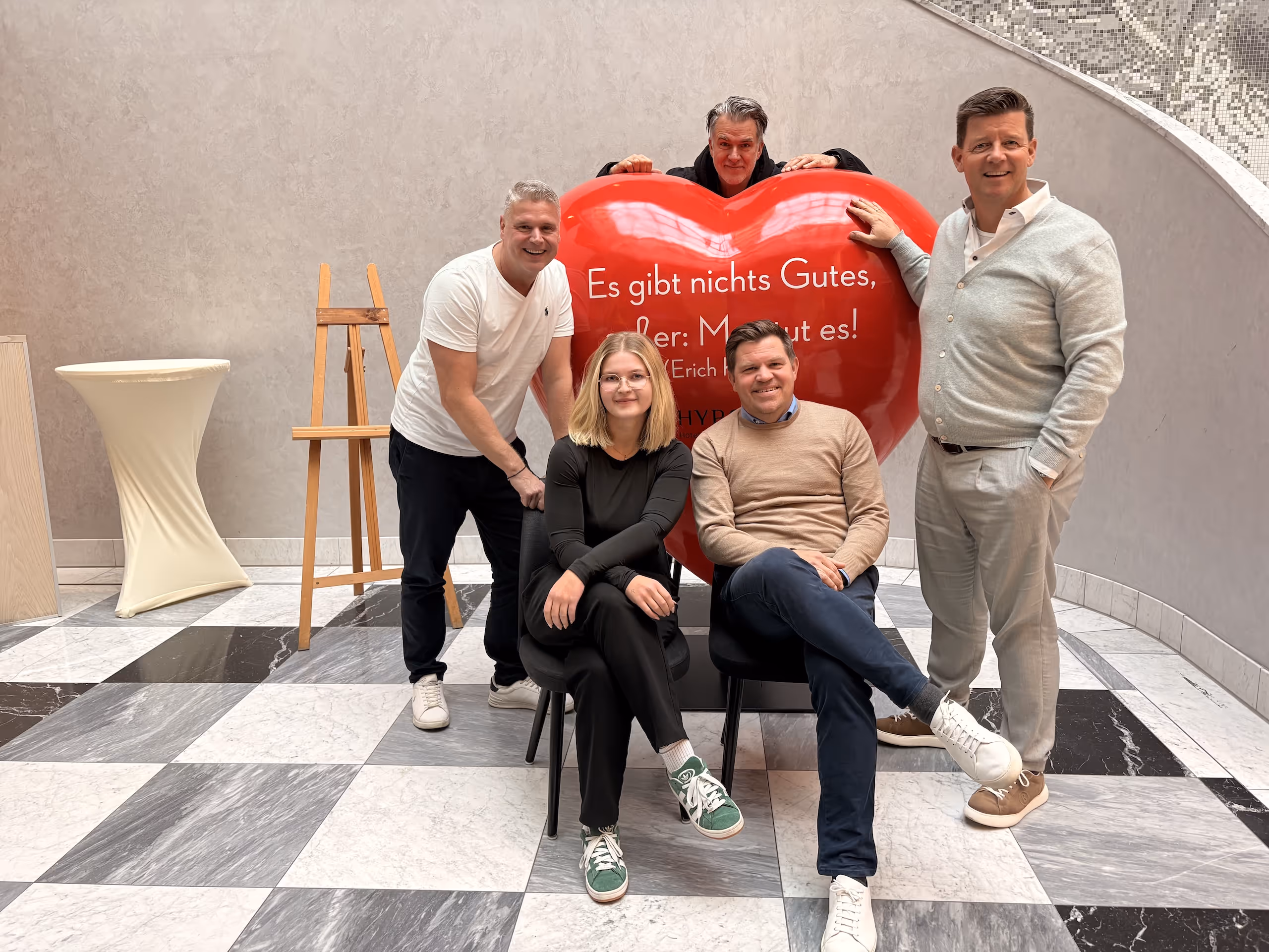 Ein Team gruppiert sich um ein großes dreidimensionales Herz