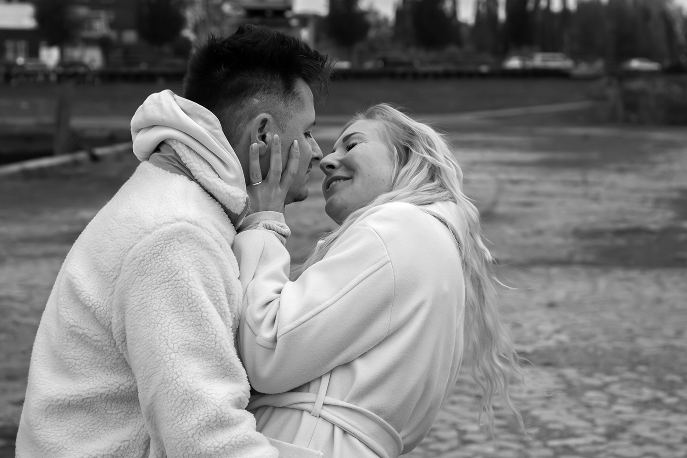 Ein verliebtes Paar steht zusammengekuschelt und ist kurz vor einem Kuss.