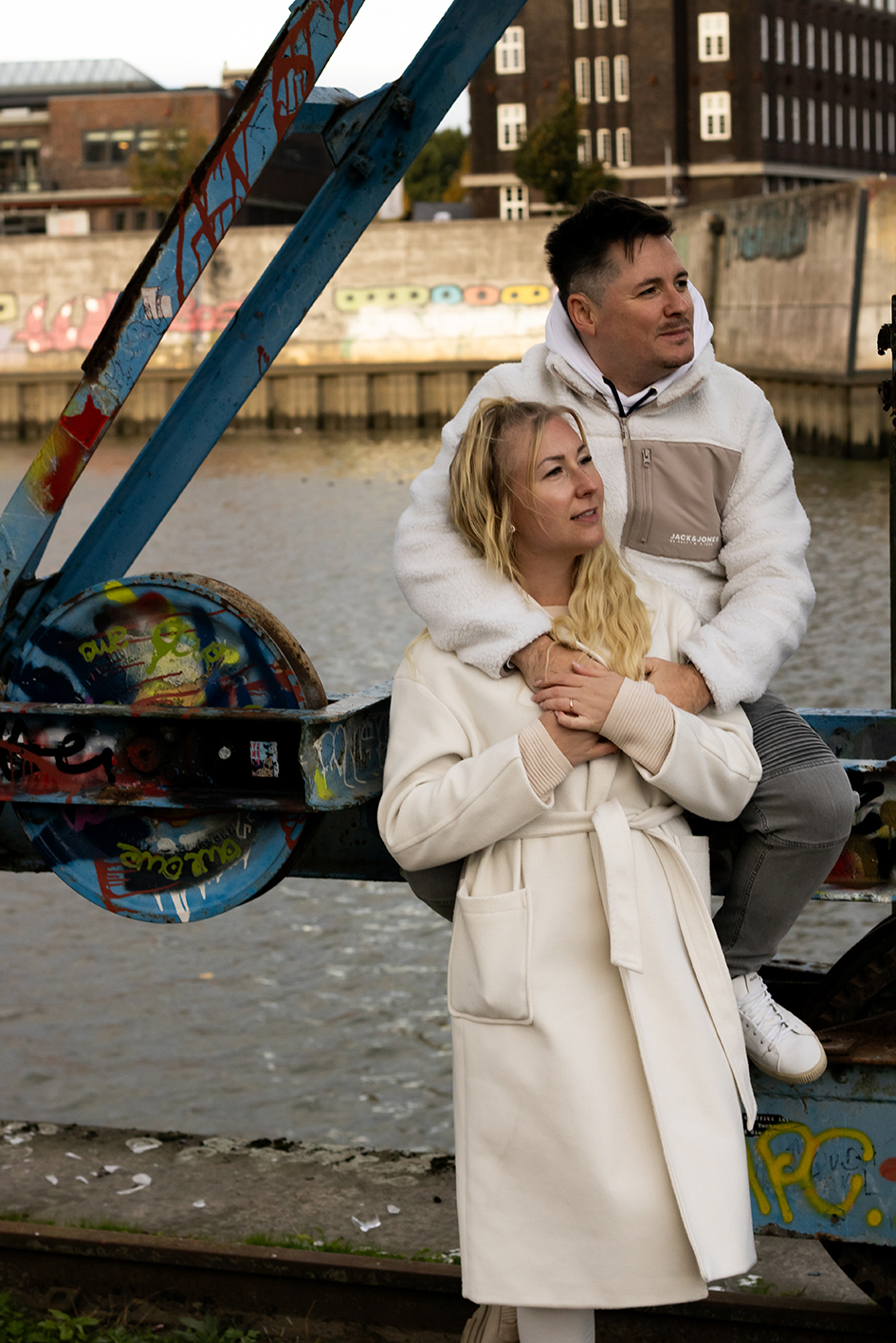 Ein Paar steht einkuschelt an einen Krahn gelehnt und schaut in die Ferne.