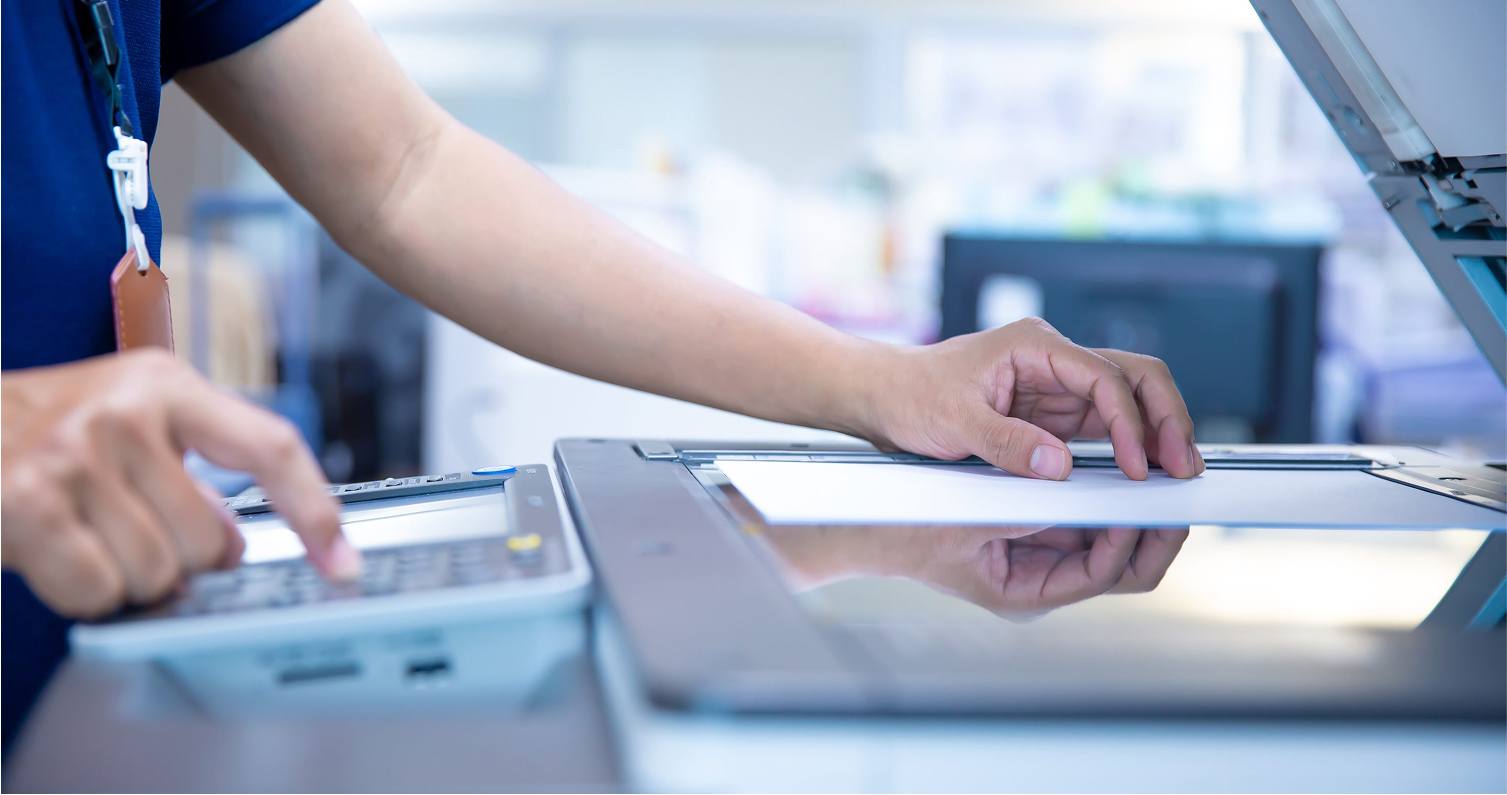 Close-up of hands signing paperwork with digital tablet nearby