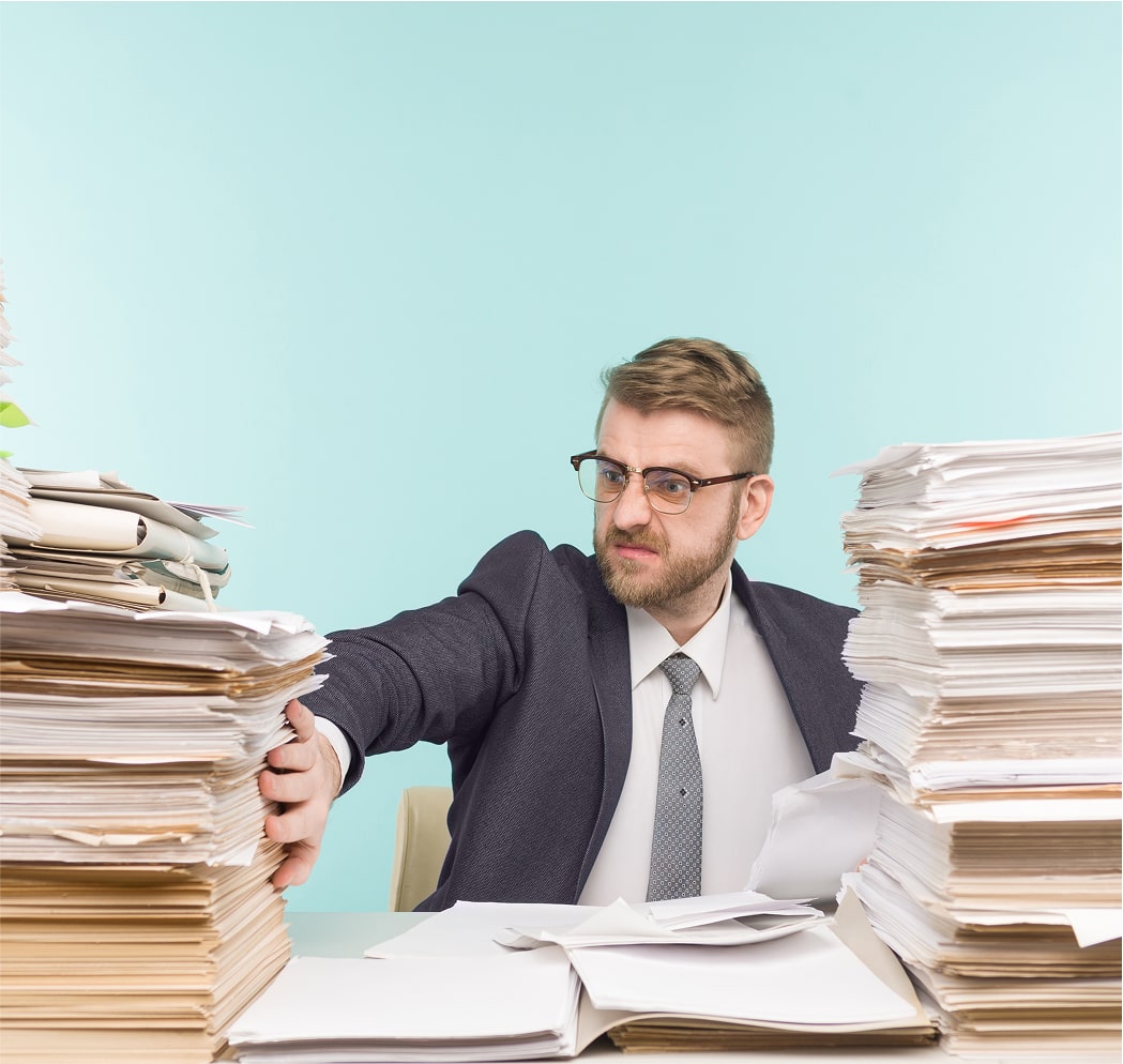 Businessman overwhelmed by tall stack of paper files