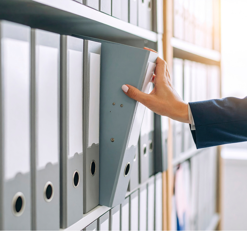 Person filing paper binders into organized archive shelf