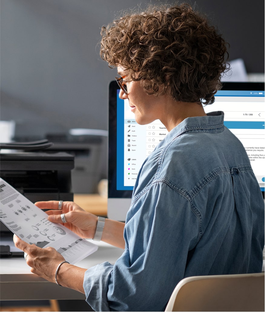 Focused woman working at desk with paperwork and computer
