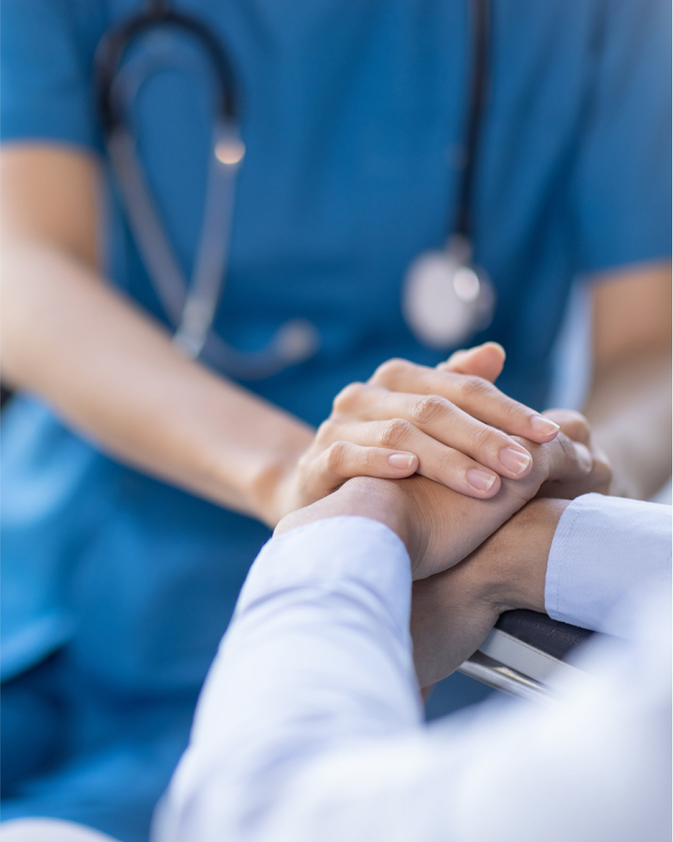 Close-up of doctor holding patient’s hand for support
