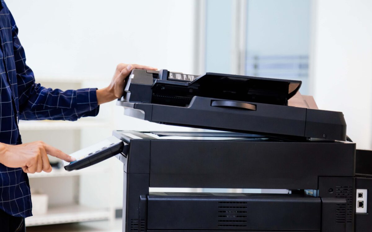 Business professional using an office scanner to digitize paper documents, representing document scanning and digital file conversion services.