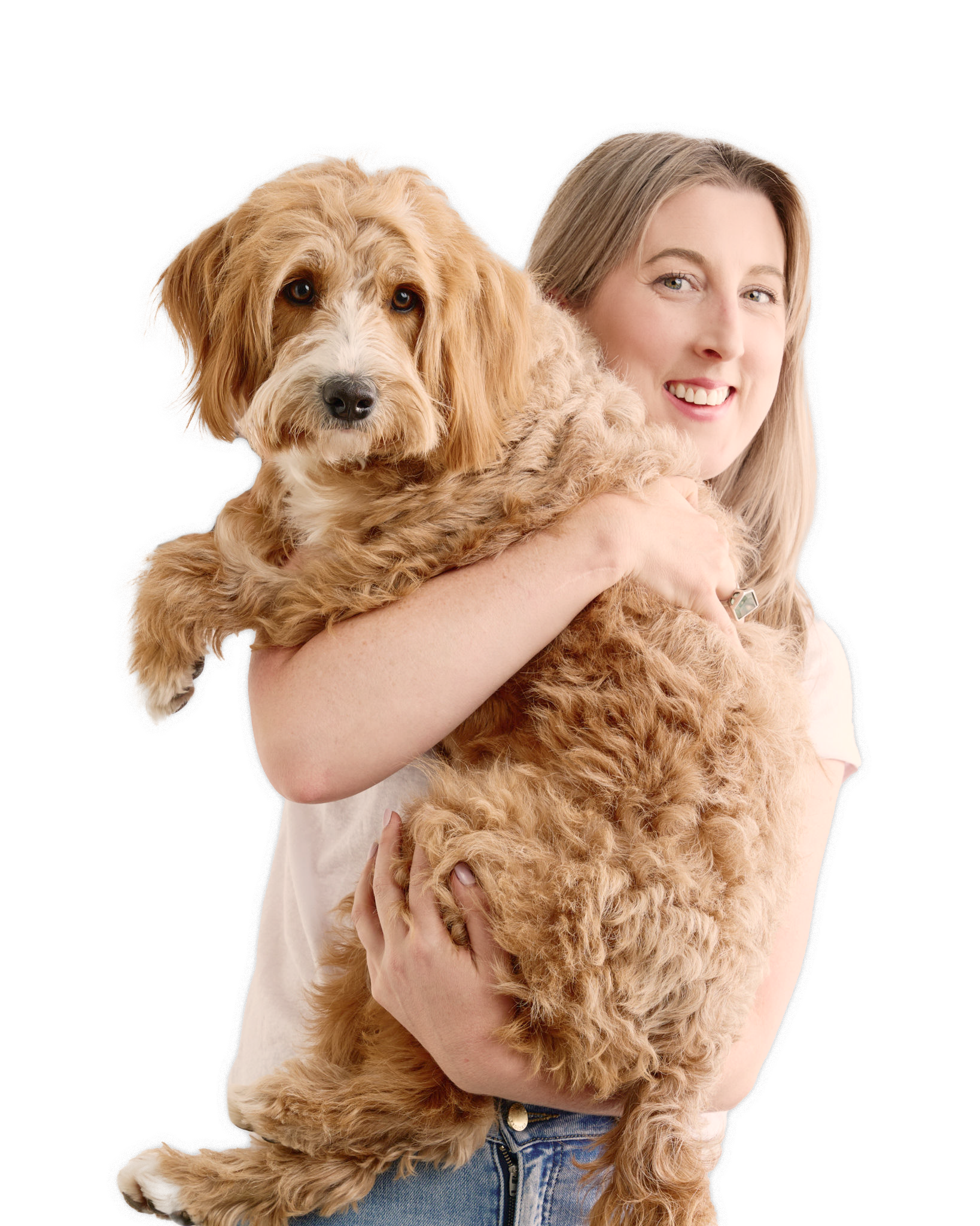 Smiling woman with light hair holding a fluffy, curly-haired tan dog.