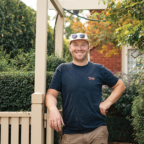 Oscar, owner of Home N Hosed, smiling outdoors at a residential property