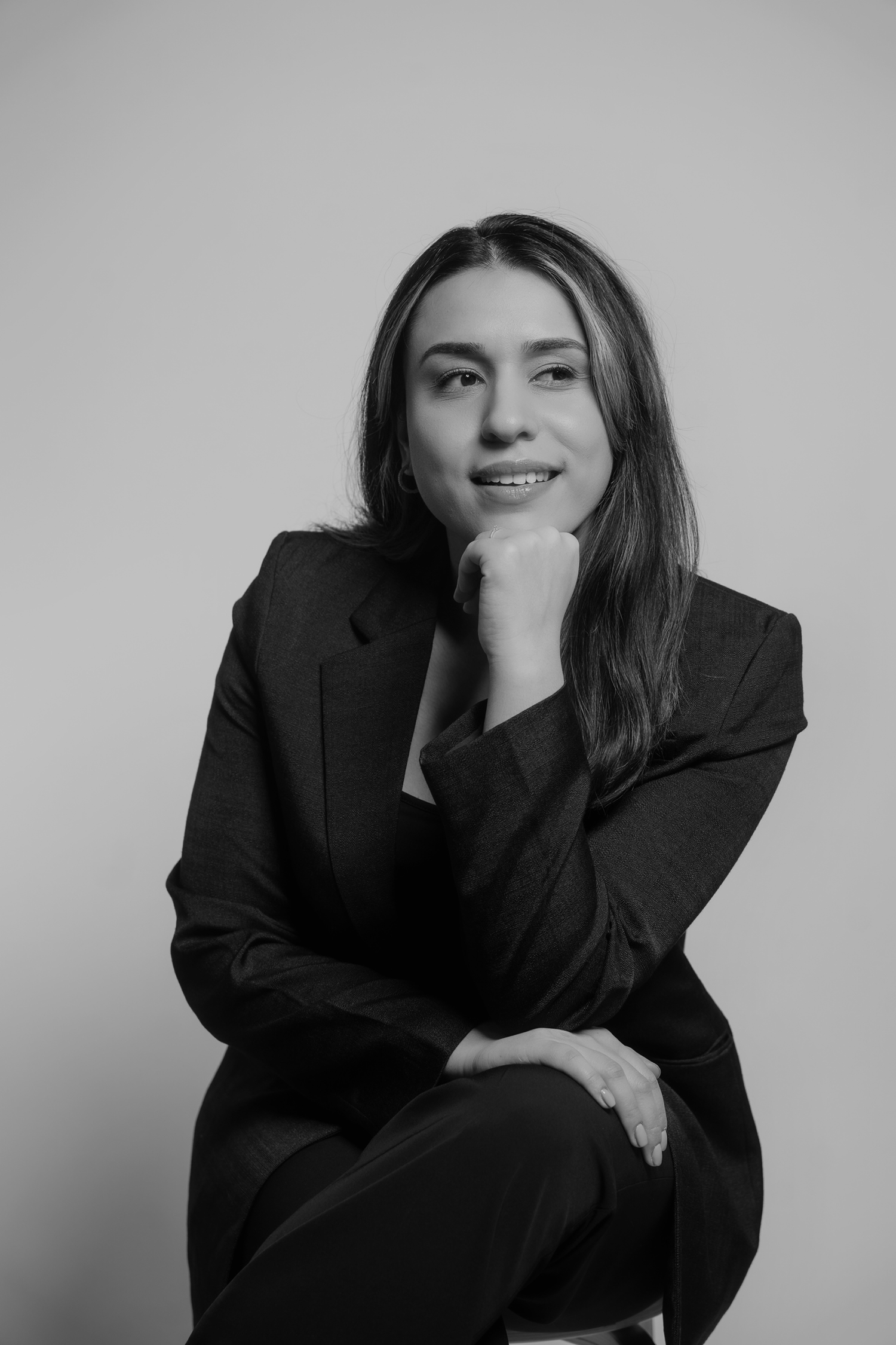 Tahmina Azizi glimlachend zittend op kruk in zwart wit