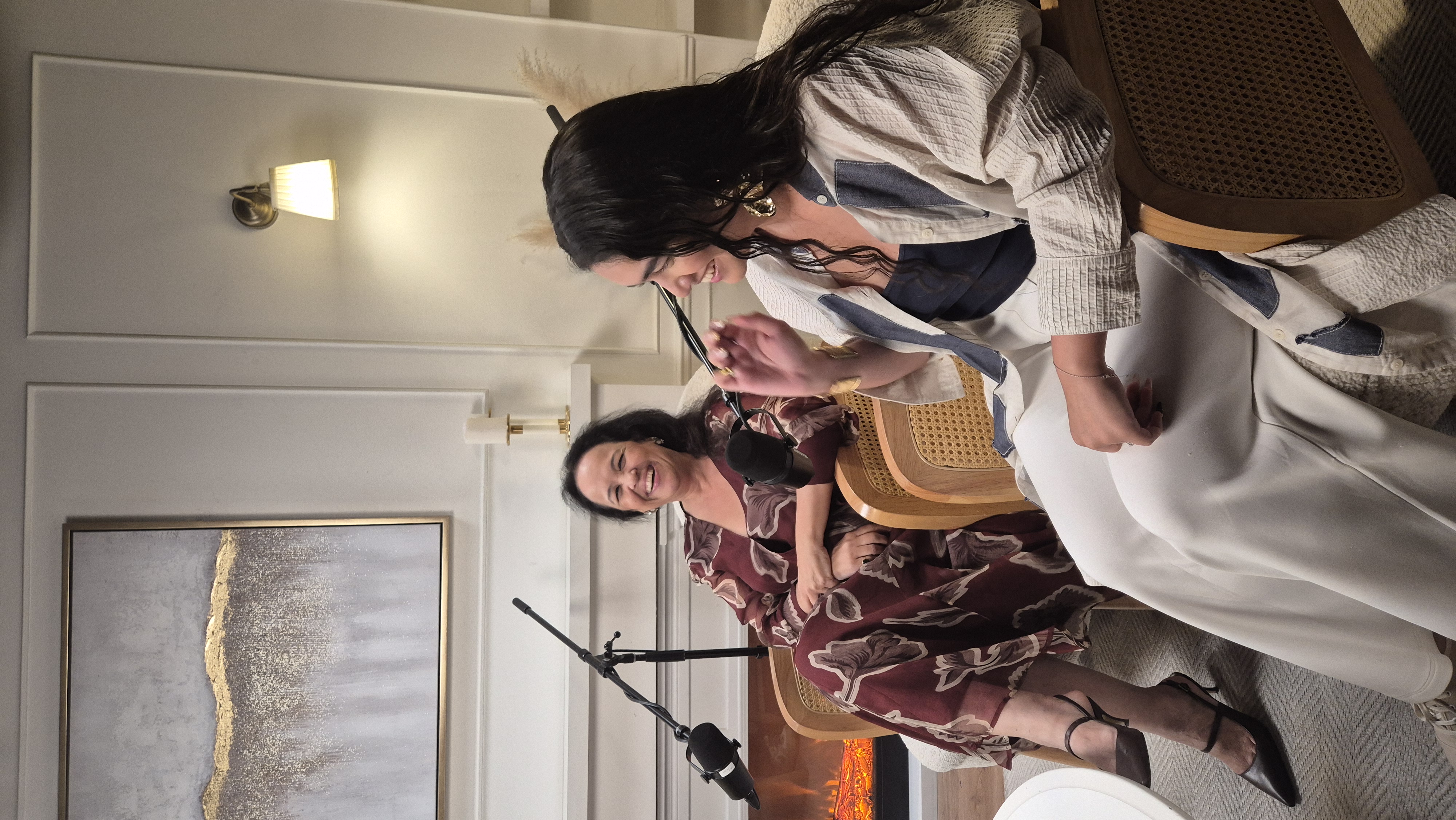A bright dining room with a dark table, white chairs, a striped bench, a rug, and a gold chandelier