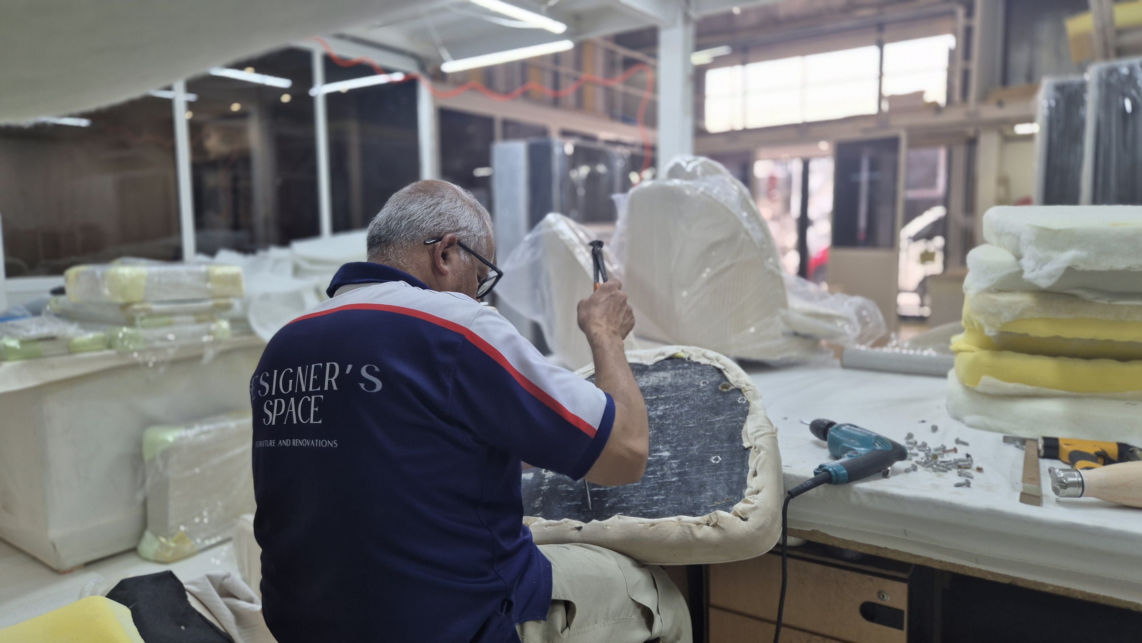 A modern bedroom with a white bed, wooden headboard, black lamp on a side table, and high windows