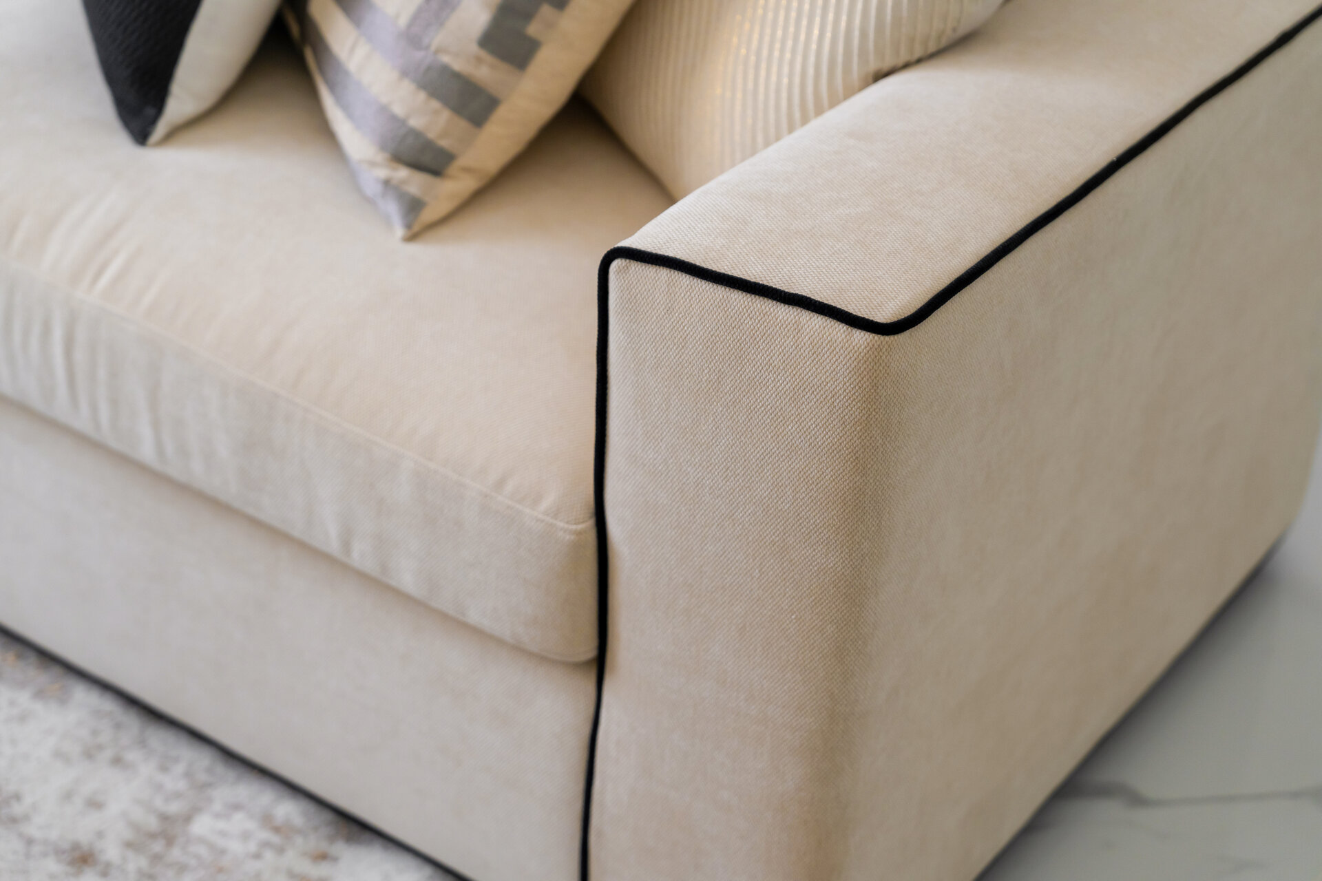 A long gray dining table with chairs in a modern home, leading into an open-plan living area. A large, multi-armed chandelier hangs above the table