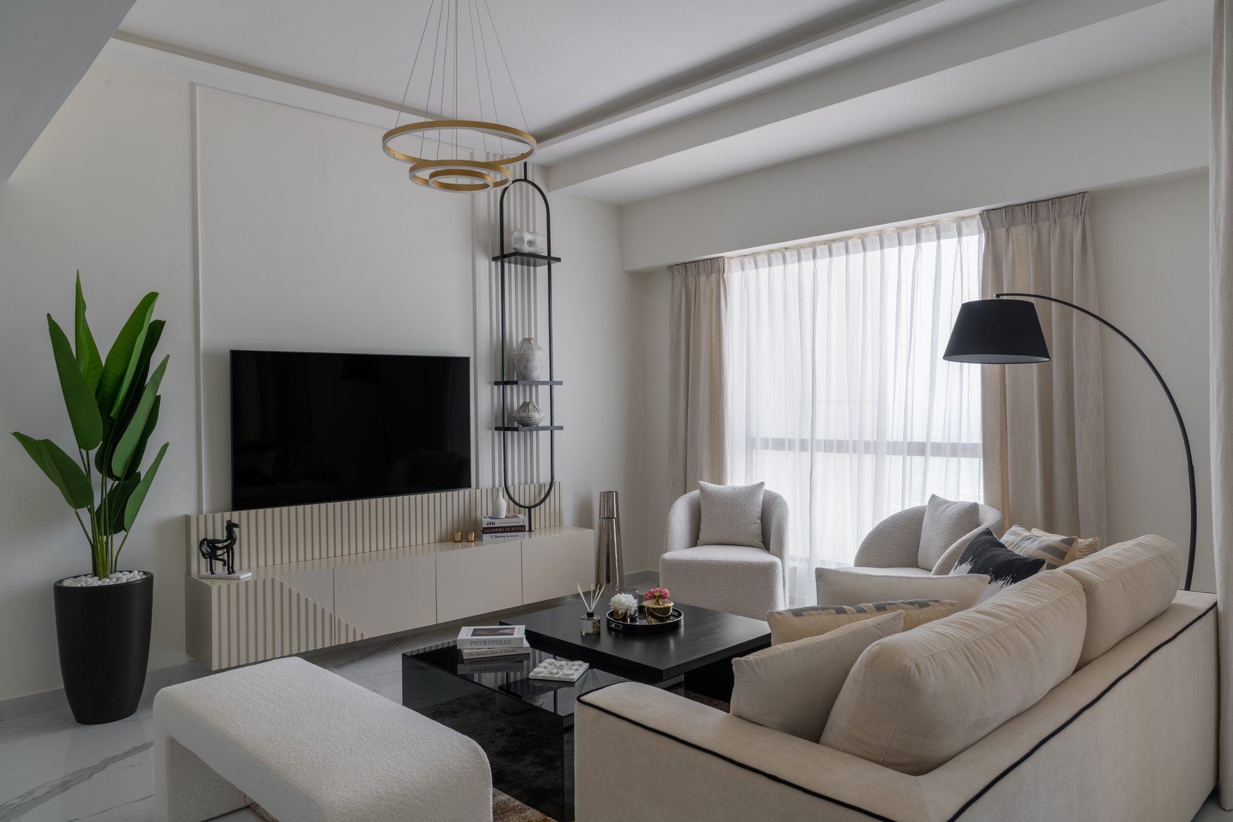 A modern black kitchen and dining area with white floors, a round dining table with chairs, and a geometrically-designed chandelier. There's also a fireplace with stacked logs on the right