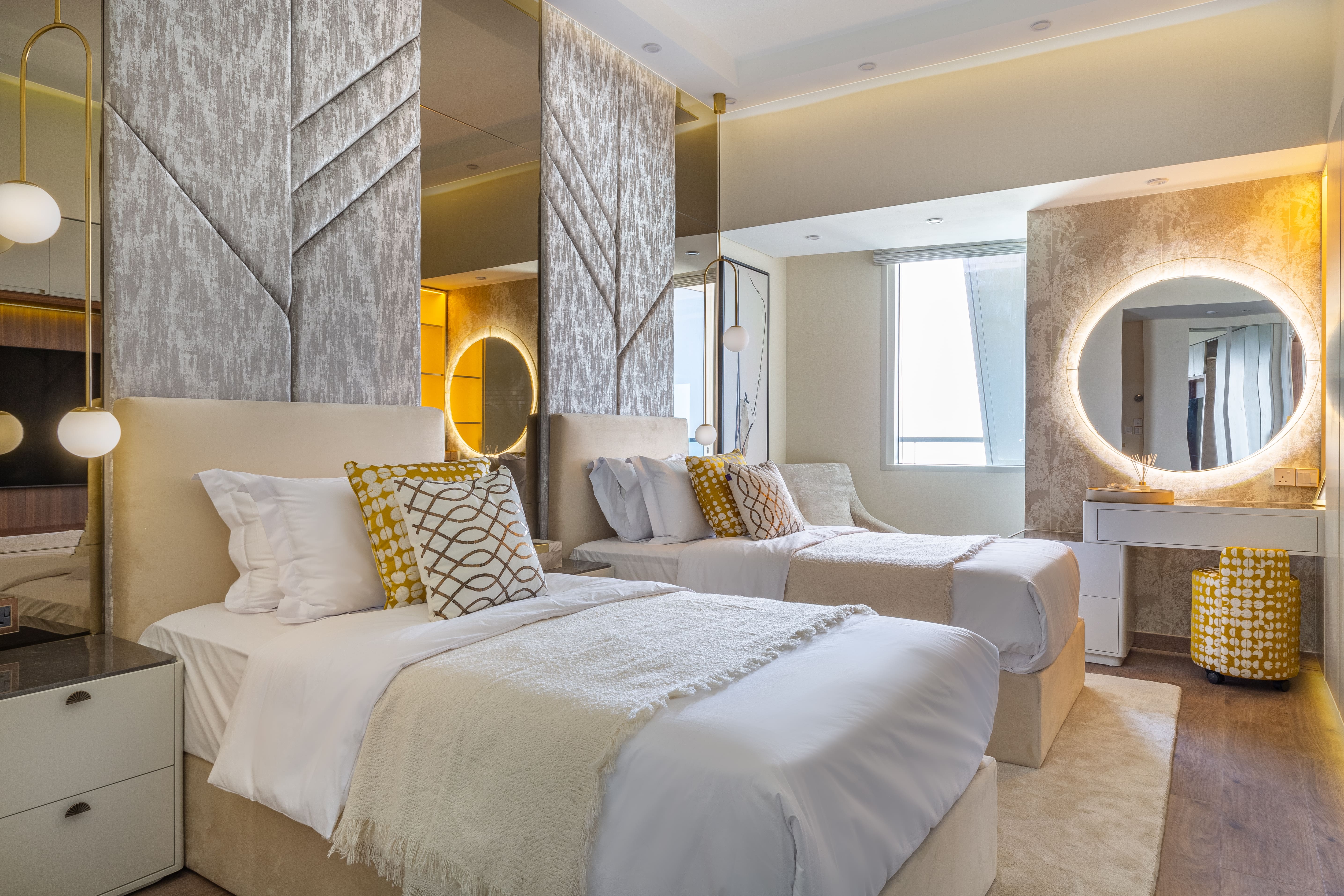 A cozy living space shows a TV mounted above a white media console, a decorative wooden ladder with a tasseled blanket, and a dining area with dark chairs visible in the background.