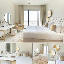 A luxurious bedroom showcases a white upholstered bed, gold chandelier, fuzzy white stools, and a black and white striped rug with a city view.