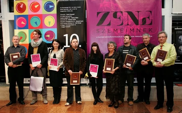 Az Arany Rajzszög díjazottjainak csoportképe a „Zene szemeimnek” plakát előtt
