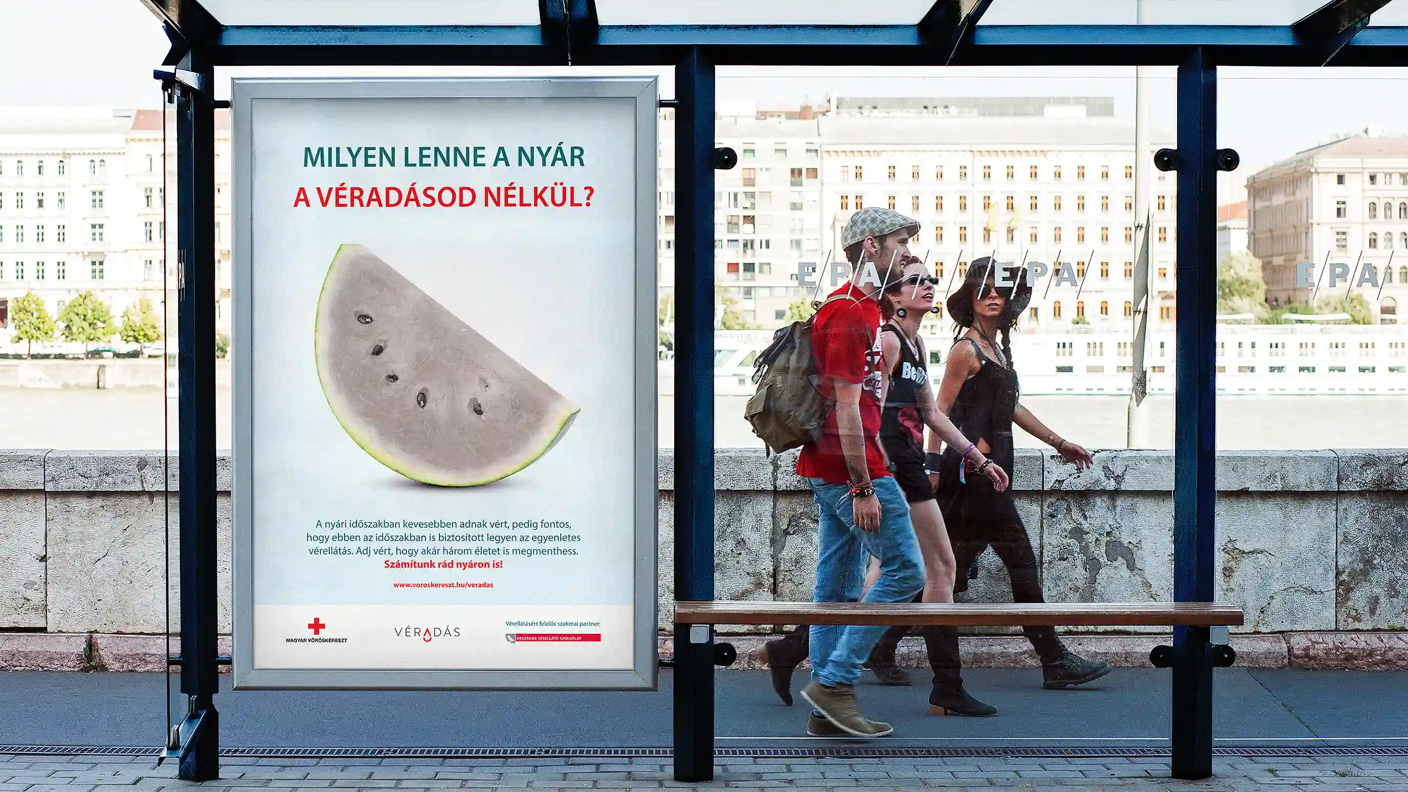 A szürke görögdinnyés véradásplakát egy buszmegállóban, járókelőkkel