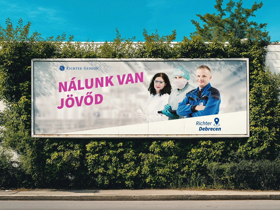 A Richter Debrecen „Nálunk van jövőd” óriásplakátja zöld sövény előtt