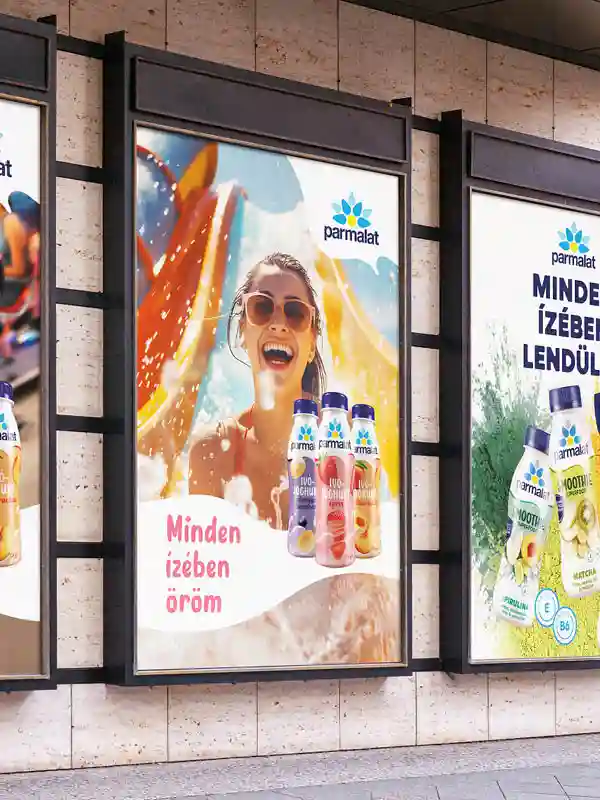 Parmalat kültéri reklám mosolygó modellel és színes italfröccsenéssel – reklámarculat és kampánydesign