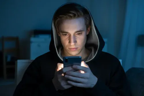 Person using smartphone in the dark representing social media anonymity and fake profiles