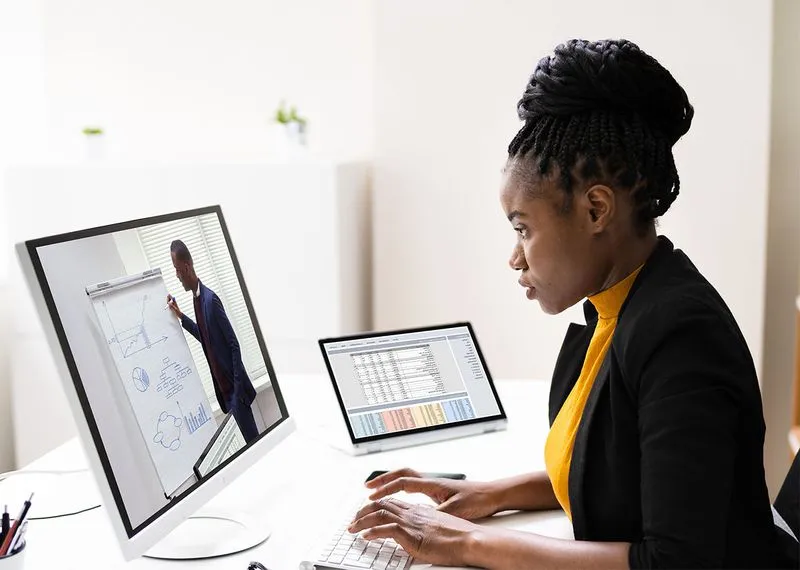 Woman watching cultural training session on desktop computer in office.