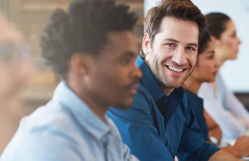 Male employee smiling while training on-site with a group.