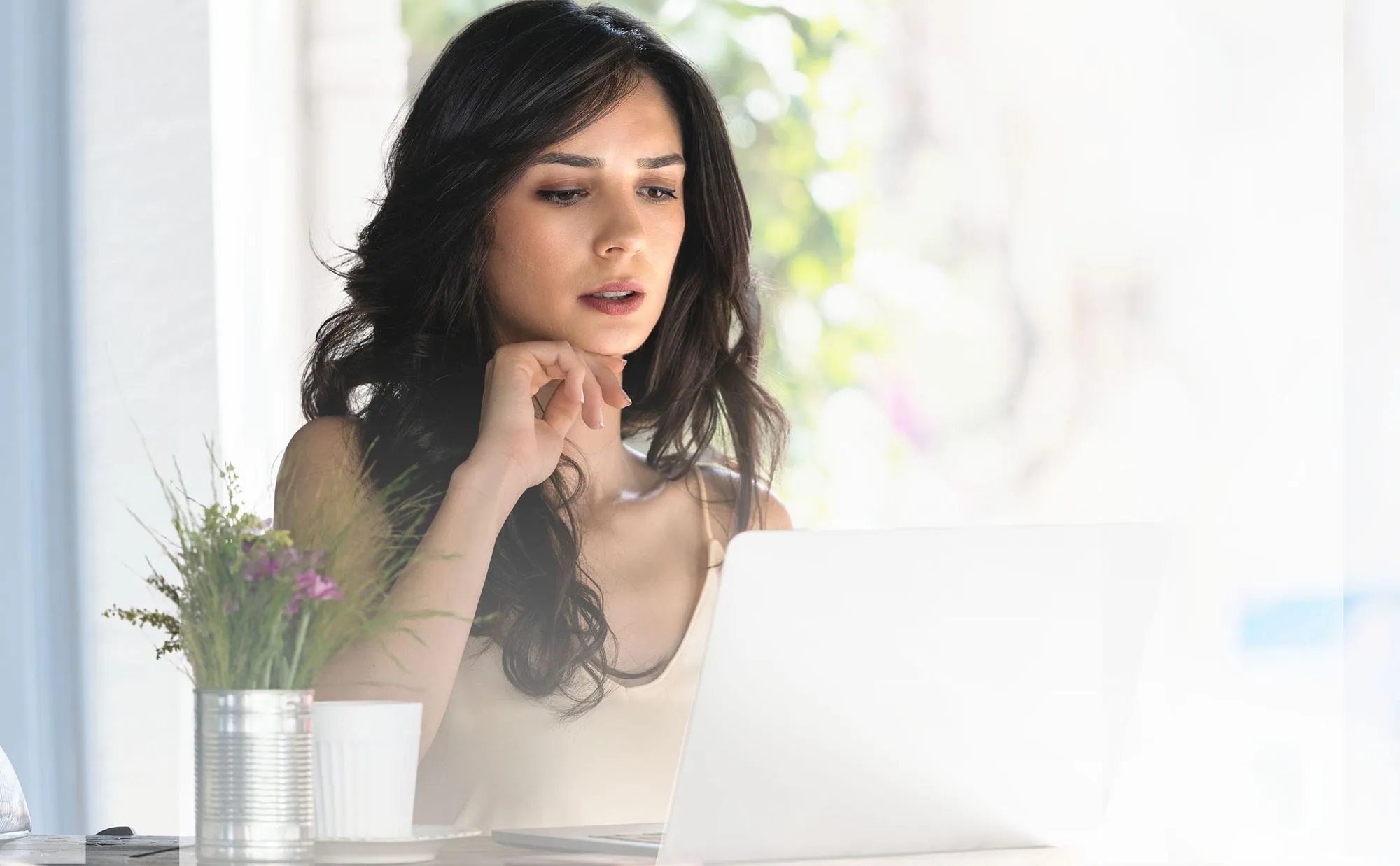 Woman working from home researching corporate relocation on laptop.