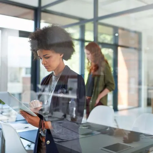 Female holding tablet in corporate office setting, checking on industry mobility trends.