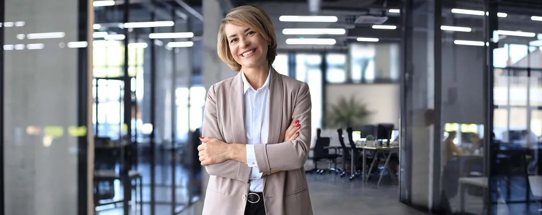 Female corporate mobility executive folding arms and smiling in downtown office.