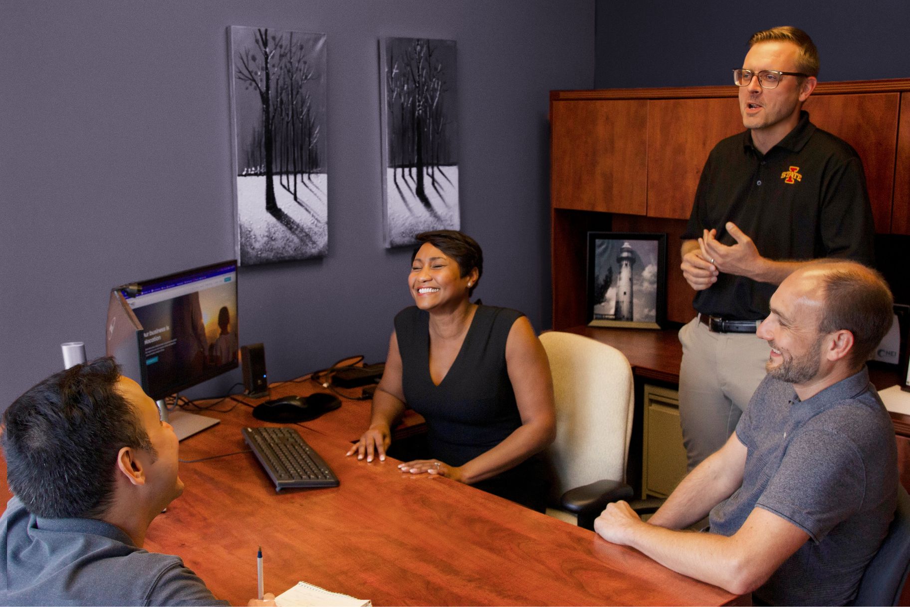 Group from NEI's Global Service Partner Relations team laughing in office.