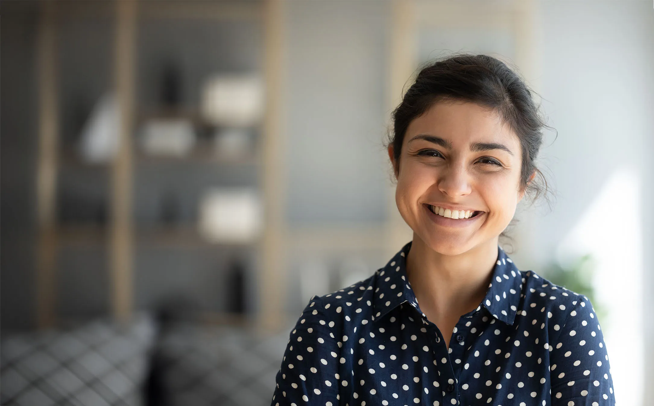 Woman in polka dot shirt smiling after receiving new job.
