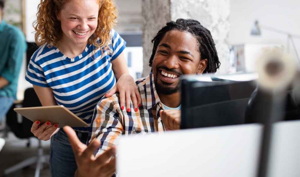 Coworkers laughing together at computer.