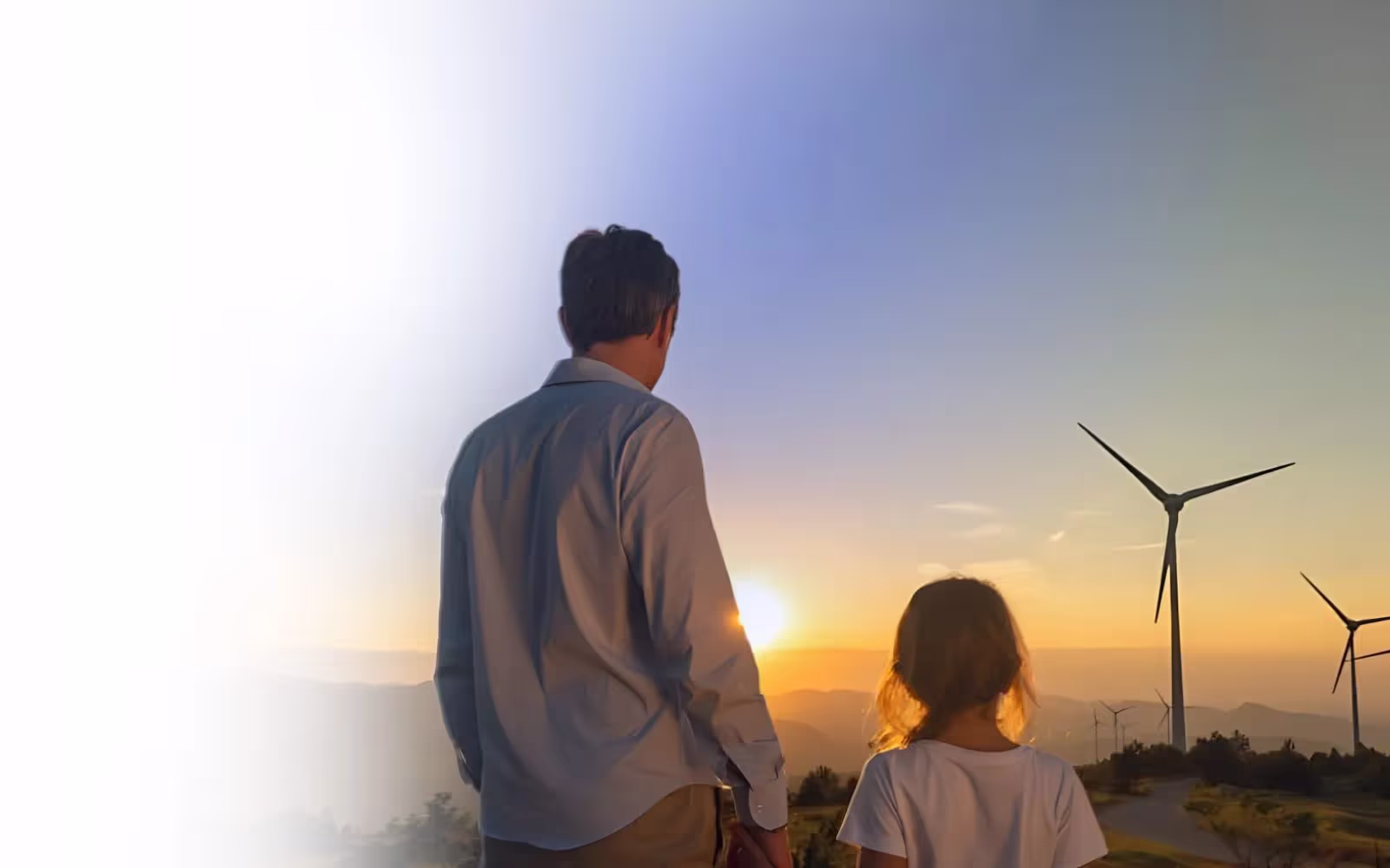 Father standing with daughter looking at sunset with windmill in the background
