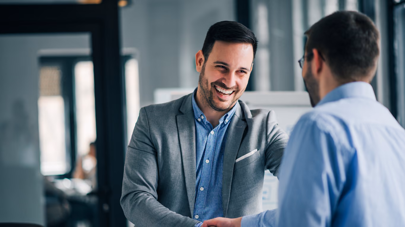 Two colleagues laughing during a handshake
