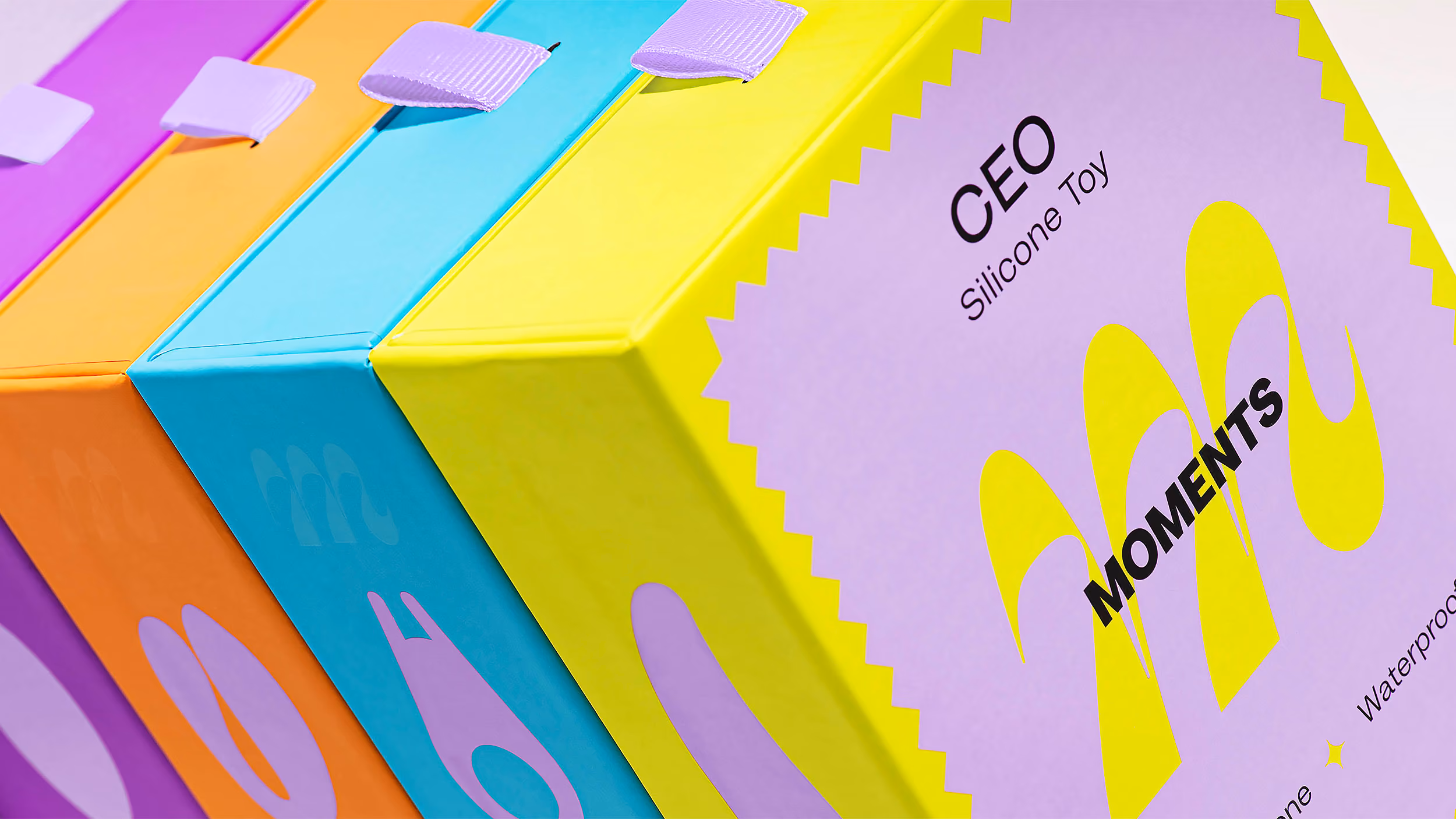 Colorful boxed silicone toys in pastel purple, orange, blue, and yellow packaging with the brand name MOMENTS.