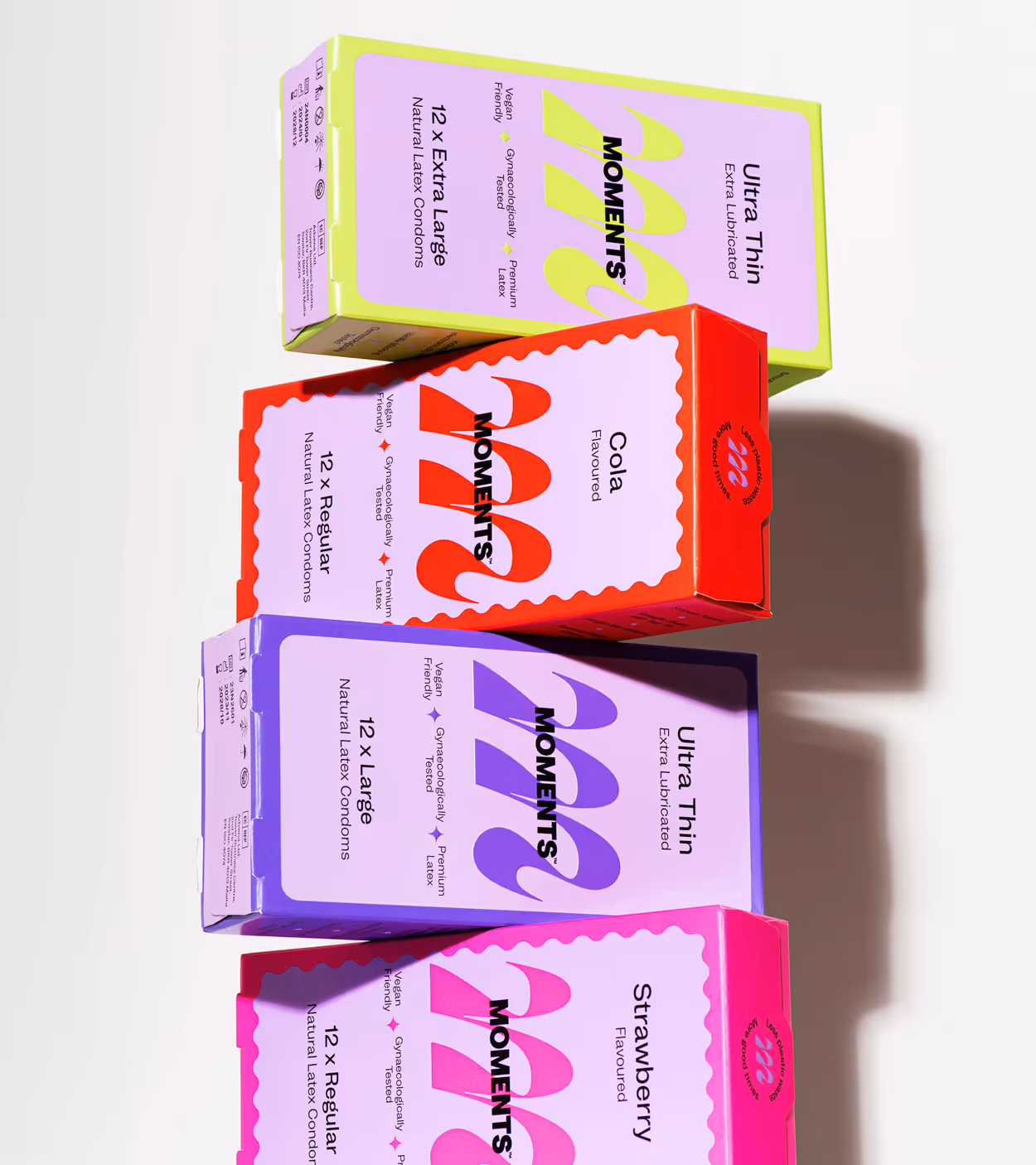 Stack of four colorful MOMENTS condom boxes in different flavors and sizes, including ultra thin extra lubricated and flavored options.